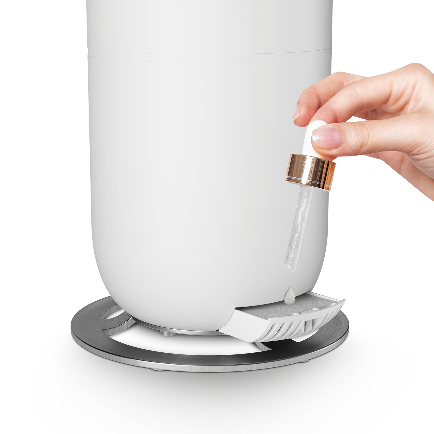 Close-up of a hand using a dropper to add fragrance to the humidifier aroma tray.