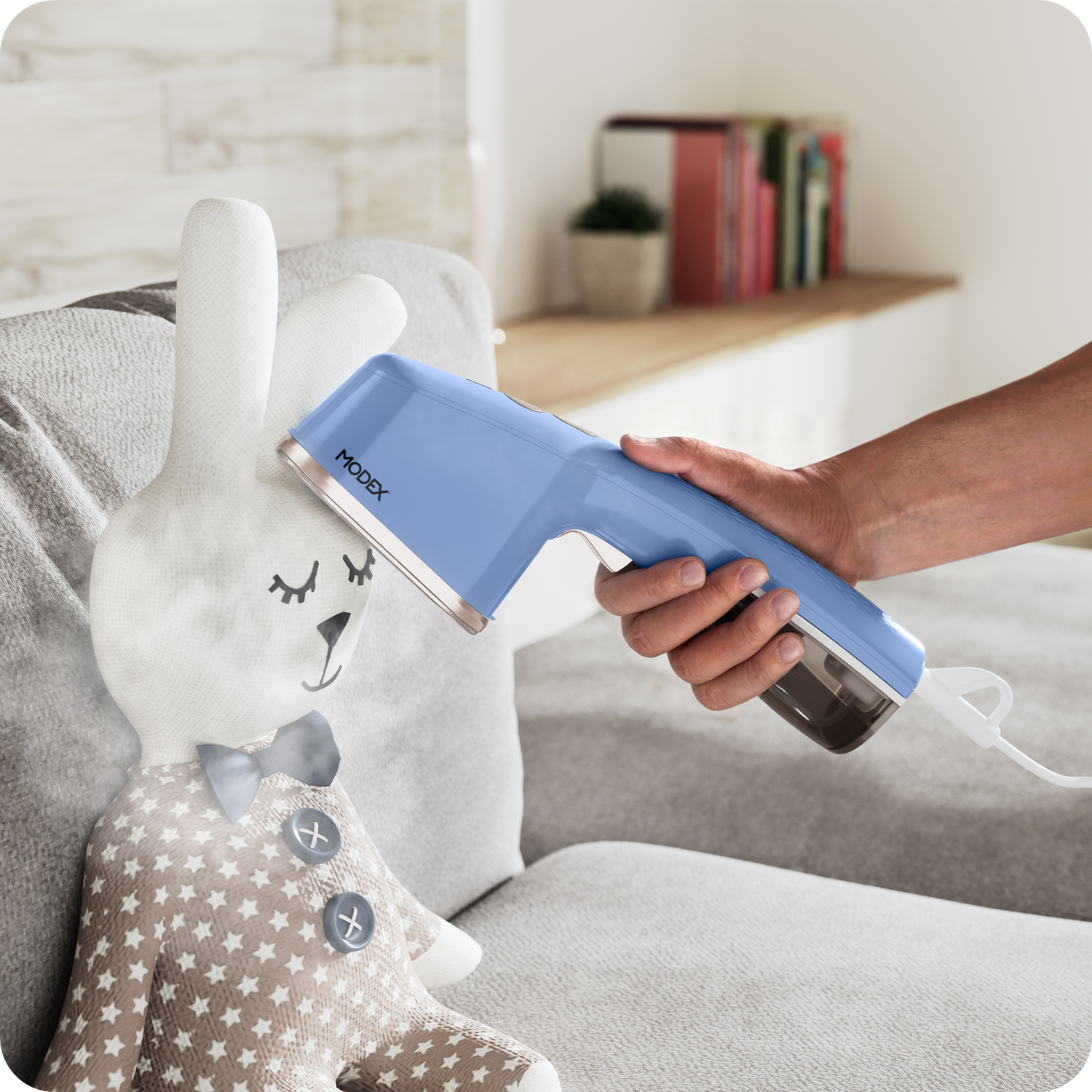 Handheld garment steamer being used on a soft fabric toy placed on a sofa.